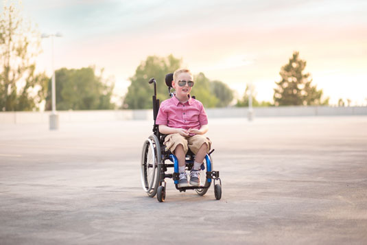 huge sunglasses on wheelchair-bound boy in schoolyard
